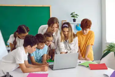 Lehrerin erklärt Ihren Schülern etwas am Laptop