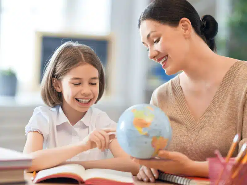 Eine Frau zeigt einem Mädchen die Erdkugel als Modell