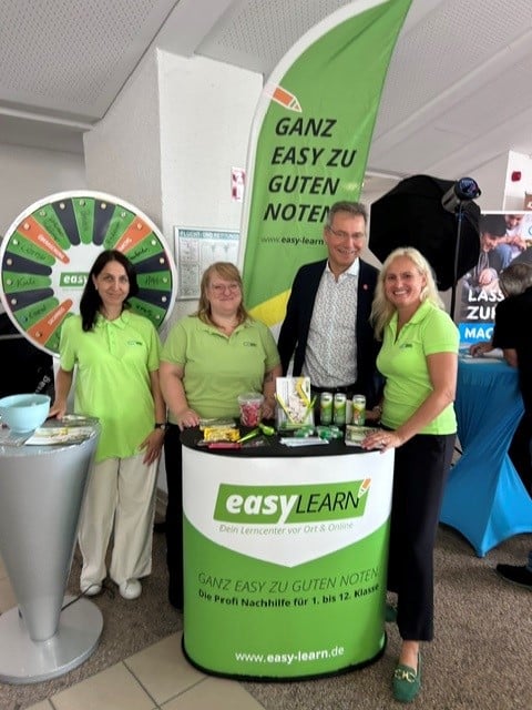 EasyLearn-Team am Messestand mit Glücksrad und Banner