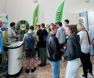 Besucher an Messestand easyLEARN mit Glücksrad und grünen Werbefahnen