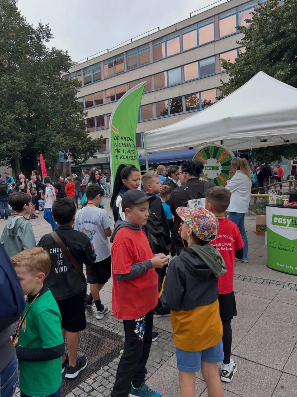 Kinder an Nachhilfe-Stand vor Schulgebäude