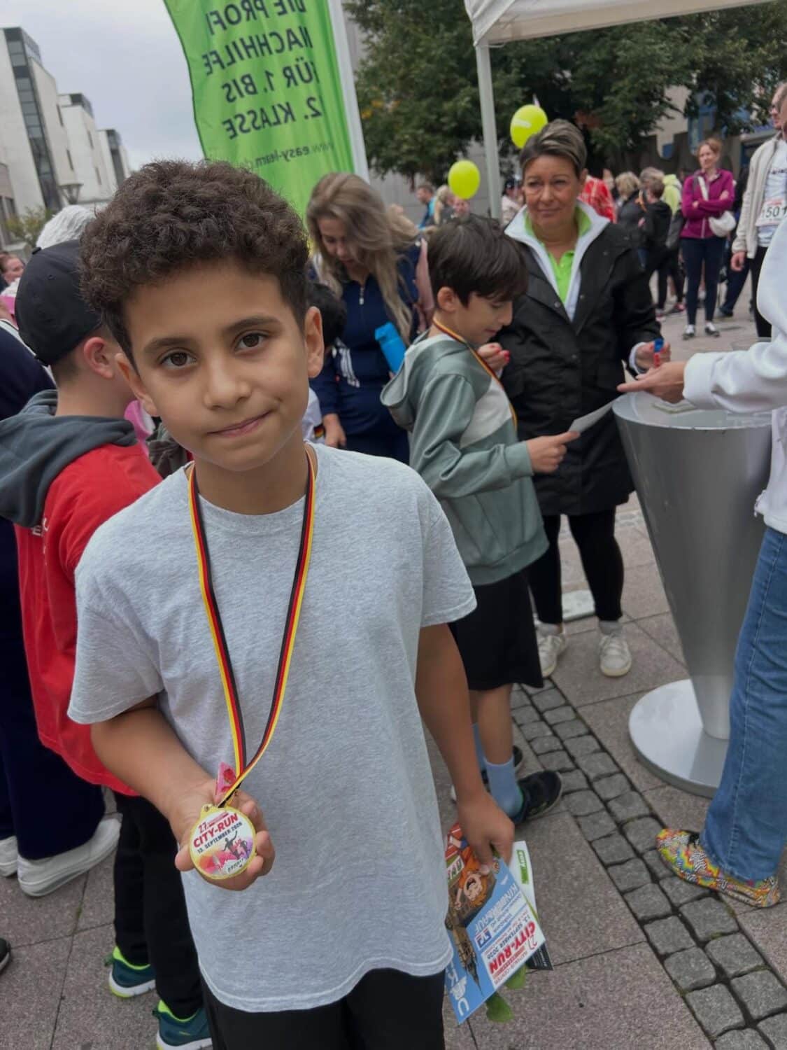 Junge zeigt Medaille nach dem City-Run