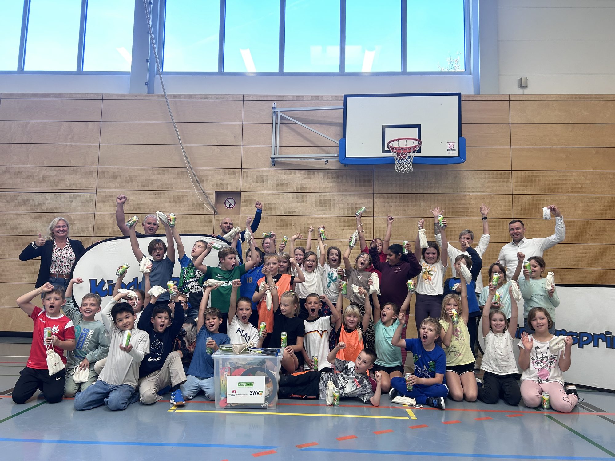 Jubelnde Kinder mit Dosen in einer Sporthalle