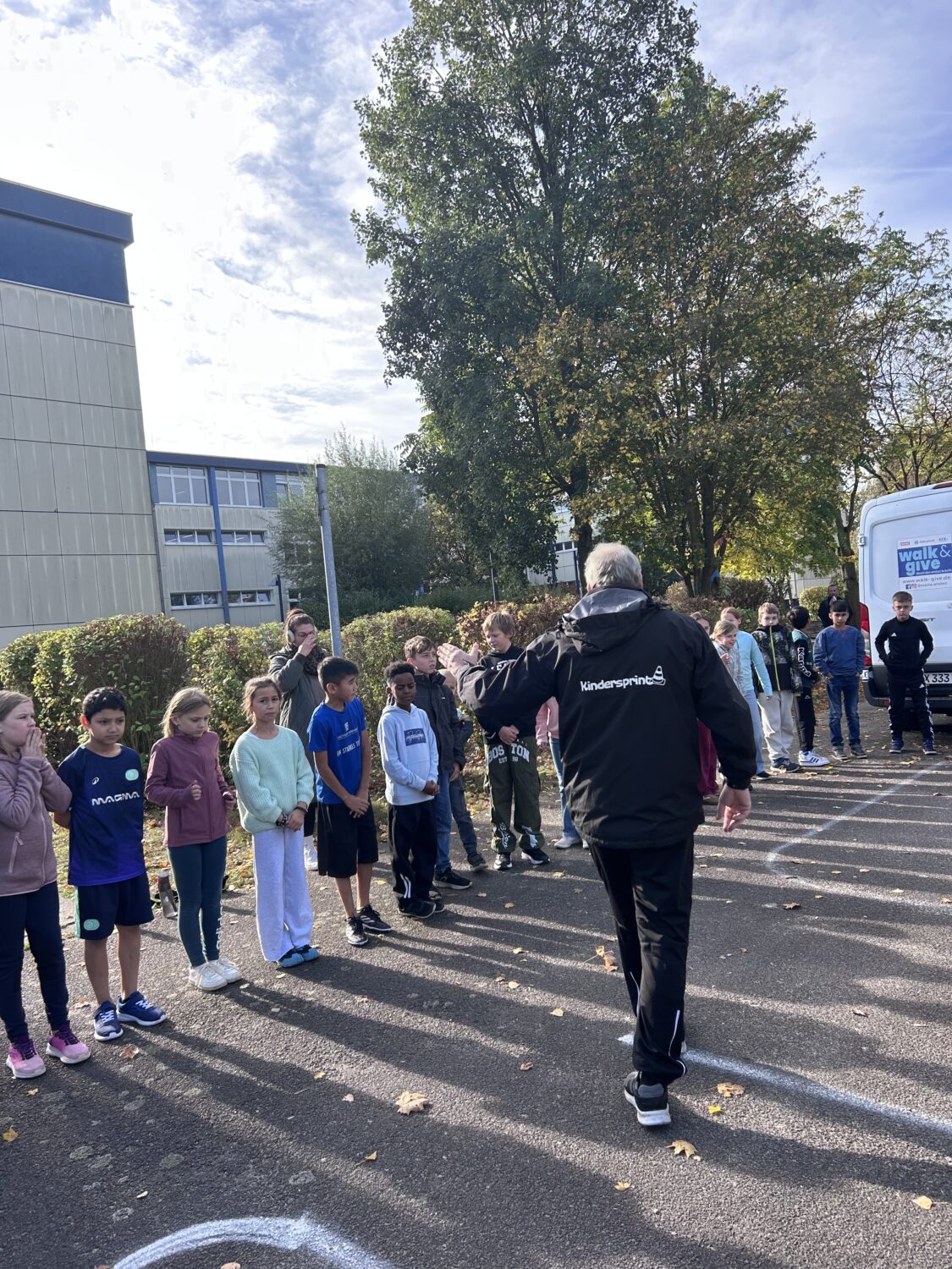 Kinder stehen bei Sportveranstaltung vor Schulgeb&auml;ude in einer Reihe