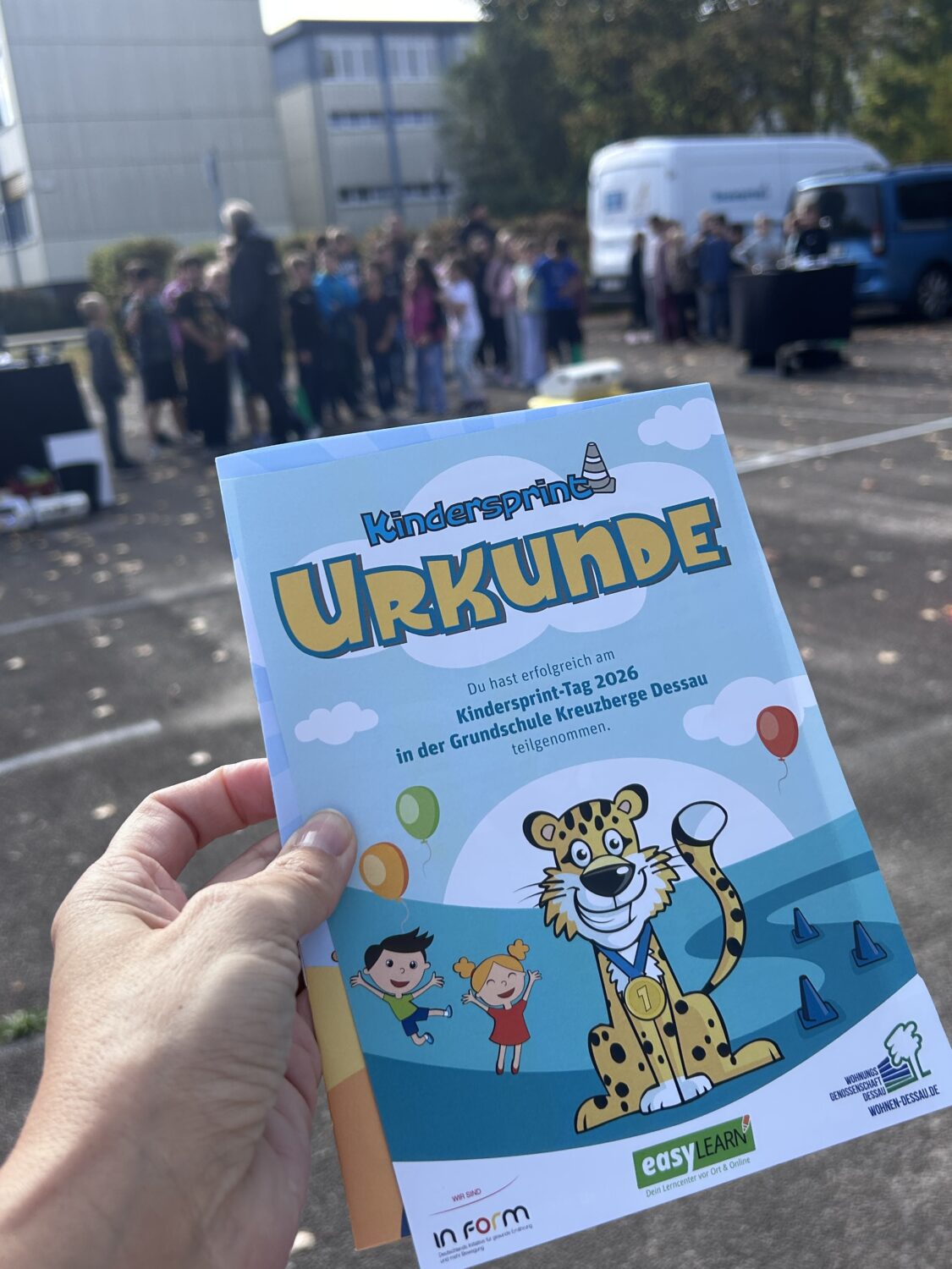 Urkunde f&uuml;r Kindersprint vor Gruppe und Fahrzeugen